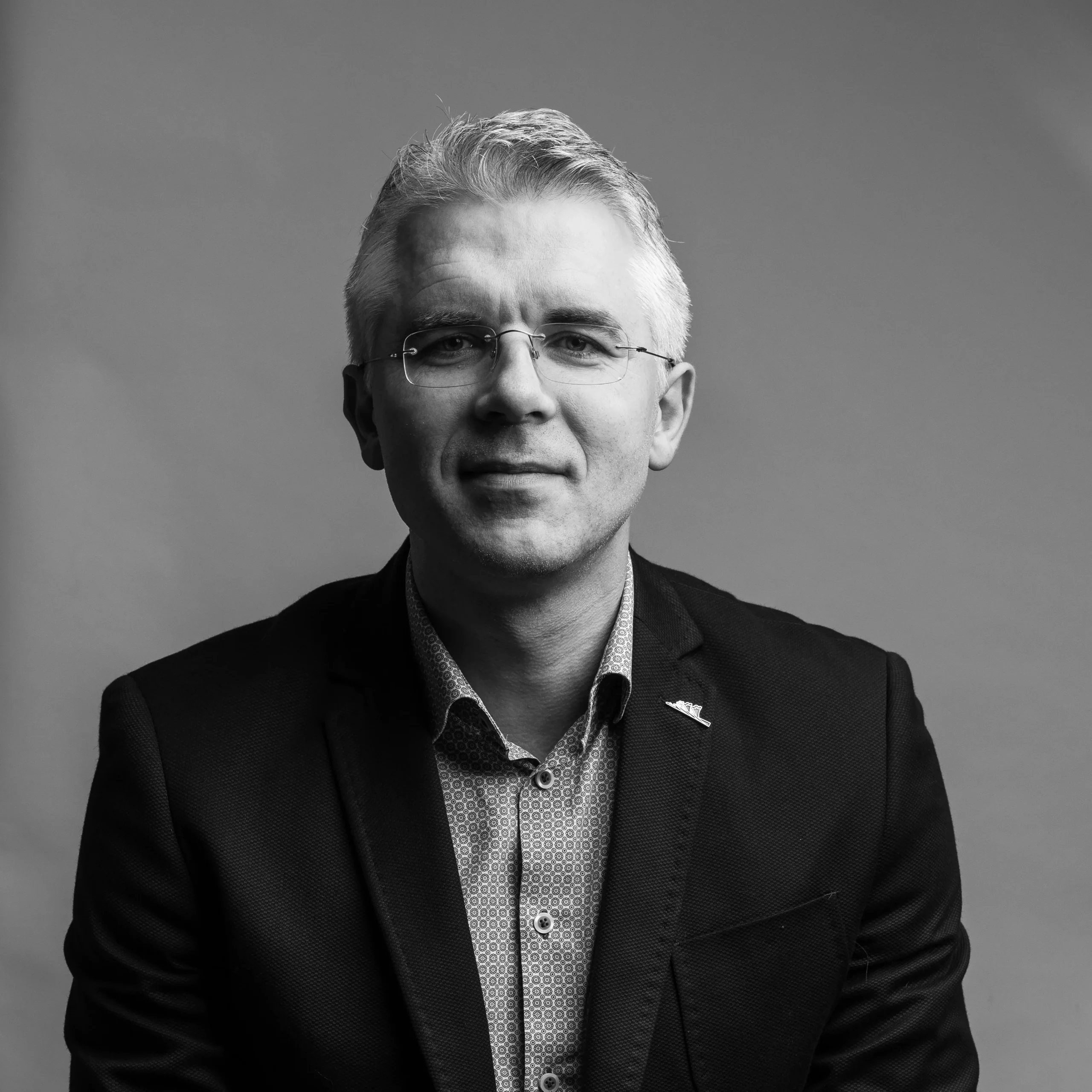 A professor in a suit and glasses is posing for a picture.