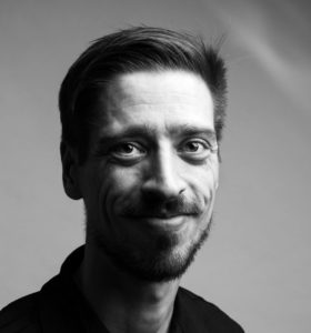 A man smiling in a neutral background