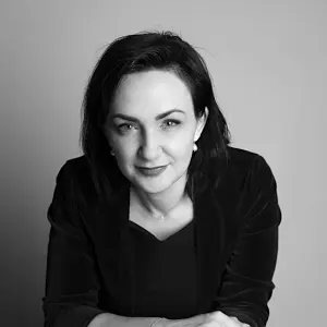 Black-haired happy professor in a black dress is posing for a picture.