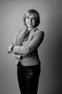 Short-haired professor is posing for a photo with her arms crossed on her chest.