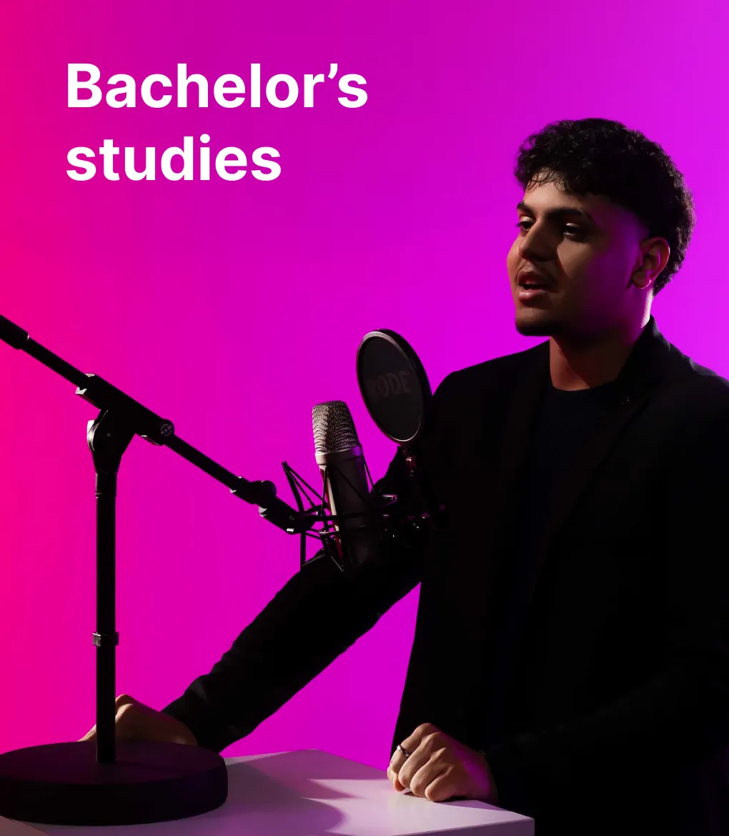 A KTU Faculty of Social Sciences, Humanities and Arts student recording audio in a studio microphone setup against a pink and violet decorative background. The faculty offers bachelor's studies. Choose KTU bachelor's studies.